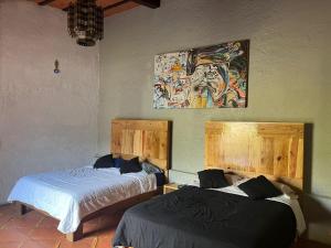 Cette chambre comprend deux lits et un tableau mural. dans l'établissement Los Cruxes, à Tepoztlán