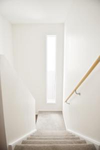 una escalera que conduce a una puerta en una habitación blanca en Johnsonville Brand New Lovely townhouse en Wellington