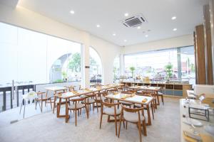 un restaurante con mesas y sillas de madera y ventanas en Two K Azana Style Hotel Bengkulu, en Bengkulu