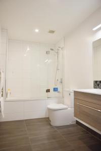 a white bathroom with a shower and a toilet at Johnsonville Brand New Lovely townhouse in Wellington