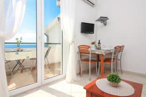 sala de estar con mesa y balcón con vistas al océano en Apartments Šara - free parking, en Primošten