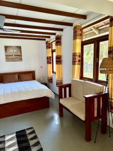 een slaapkamer met een bed, een stoel en ramen bij 108 Palms Beach Resort in Trincomalee