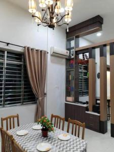 una sala da pranzo con tavolo, sedie e lampadario pendente di sibu muhibbah homestay a Sibu