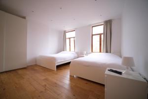 two beds in a white room with two windows at Smart Appart - City Center in Brussels