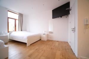 a white bedroom with a bed and a television at Smart Appart - City Center in Brussels