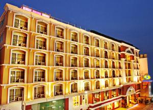 Intimate Hotel Pattaya - SHA Extra Plus في باتايا سنترال: مبنى أصفر كبير مع العديد من النوافذ في الليل