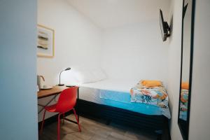 a bedroom with a bed and a desk and a red chair at Tequila Sunrise Hostel in Guatemala