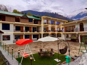 a hotel with chairs and a swing in the yard at Manali Hotel Beas River Retreat in Manāli