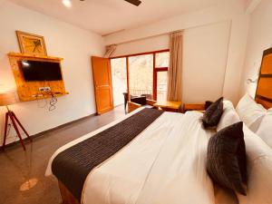 a bedroom with a large bed and a tv at Manali Hotel Beas River Retreat in Manāli