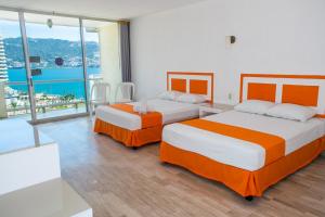 two beds in a room with a view of the ocean at Romano Palace in Acapulco