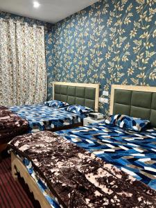 Duas camas num quarto com papel de parede azul e branco em Tripzigo hotel em Srinagar