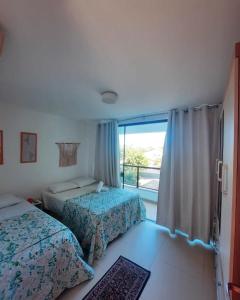 een slaapkamer met 2 bedden en een groot raam bij Imbassaí Solaris Ap Beach in Imbassai