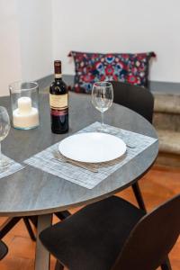 una mesa con un plato blanco y una botella de vino en La casa di Ugo-a due passi dal Duomo, en Florencia