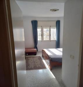 1 dormitorio con 1 cama y una ventana con cortinas azules en Joli studio, 17 Avenue Hedi Nouira Ennasr 2, Ariana, Tunis, en Ariana