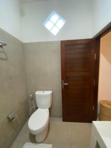 a bathroom with a toilet and a wooden door at Made Misi Homestay in Penginyahan