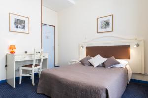 a bedroom with a bed with a desk and a bed sidx sidx sidx at Logis Hôtel Central in Montargis