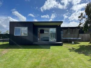 a black tiny house in a yard at Black Beauty - Double Family Lake House for 12 with a NEW SPA & Pets in Mangakino