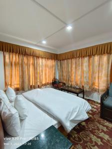 a bedroom with a large white bed and curtains at Royal galaxy in Pahalgām