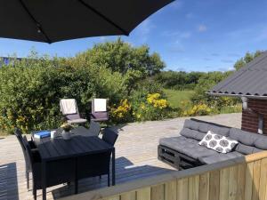 a patio with a couch and a table and chairs at Summerhouse Near The Limfjord And The Western Sea in Vestervig