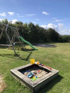 a sandbox in the grass next to a playground at Summerhouse Near The Limfjord And The Western Sea in Vestervig