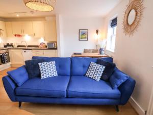 a blue couch in a living room with a kitchen at Stoker's Rest in Whitby
