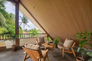 eine Veranda mit Stühlen und einem Tisch und einigen Pflanzen in der Unterkunft The Vinaya Boutique Hotel in Ubud