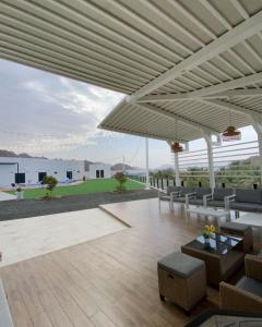 a patio with chairs and tables and a large white pergola at Sheema Lodge in Hatta