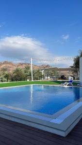 a large swimming pool with blue water and mountains in the background at Sheema Lodge in Hatta