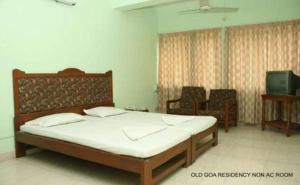 a bedroom with a large bed and a tv at Old Goa Residency in Old Goa