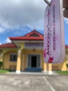 una botella de vino frente a una casa en ANGGERIK IMPIAN HOTEL -Best for Travellers at Kuala Berang, en Kuala Berang