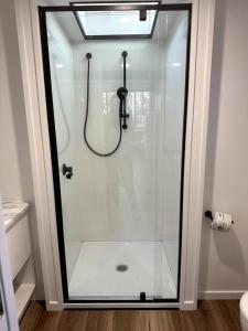 a shower with a glass door in a bathroom at Tiny Home + Donkeys + Alpacas in Tamborine