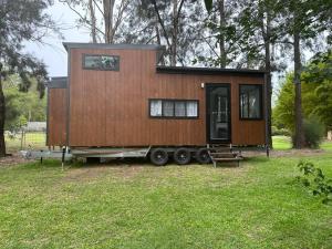 a tiny house on a trailer in a field at Tiny Home + Donkeys + Alpacas in Tamborine