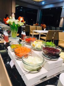 a buffet with bowls of vegetables on a counter at Mayflower Grande Suite Hotel in Phitsanulok