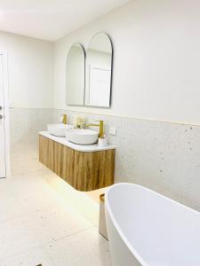 a white bathroom with two sinks and a tub at Deluxe Queen Studio Fully Self Contained- Living, kitchenette, laundry, bedroom, bathroom, parking, Wifi, - Free shuttle Service in Gold Coast