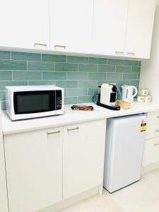 a kitchen with a white counter top with a microwave at Deluxe Queen Studio Fully Self Contained- Living, kitchenette, laundry, bedroom, bathroom, parking, Wifi, - Free shuttle Service in Gold Coast