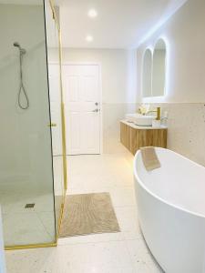 a bathroom with a tub and a glass shower at Deluxe Queen Studio Fully Self Contained- Living, kitchenette, laundry, bedroom, bathroom, parking, Wifi, - Free shuttle Service in Gold Coast