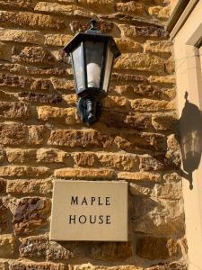 a street light on a stone wall with a sign at Maple House 