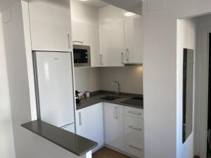 Una cocina con gabinetes blancos y un refrigerador. en Renovated and Cozy Apartment, en Mareny Blau