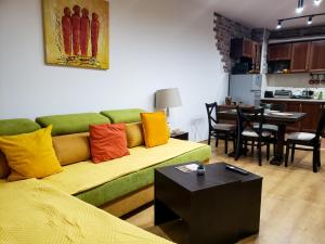 a living room with a green couch with colorful pillows at Semiramida gardens Apartment 23 in Borovets