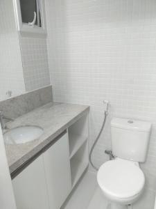 Baño blanco con aseo y lavamanos en APARTAMENTO smart PITUBA 5, en Salvador