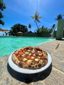 une pizza assise sur une assiette à côté de l'eau dans l'établissement Casa Smeralda, à Dikwella