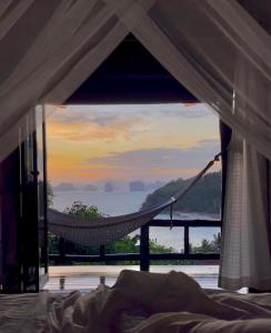 a hammock in a bedroom with a view of the ocean at Hillhouse - Koh Yao Noi in Ko Yao Noi