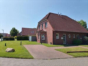 a red brick house with a grass yard in front of it at Ferienhaus Finkenburg im Herzen Ostfrieslands in Wirdum