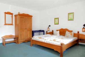 ヴァンドリッツにあるHotel am Liepnitzseeのベッドルーム1室(木製ベッド1台、木製キャビネット付)