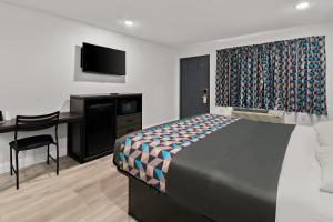 een slaapkamer met een bed, een bureau en een televisie bij Rodeway Inn in Palestine