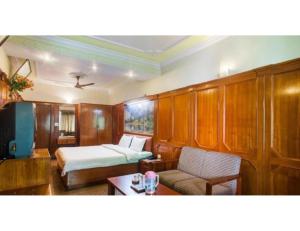 a bedroom with a bed and a couch and a table at Hotel Valley View, Mussoorie in Mussoorie