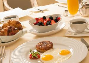 a table with a plate of breakfast food and a bowl of fruit at Hotel Day In Emporium in Lahore