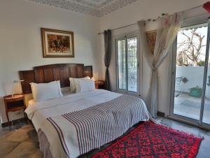 a bedroom with a large bed with a red rug at Dar Souad in La Marsa