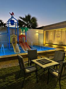 a table and chairs in front of a playground at Tola Holiday House Al Rimal in Riyadh