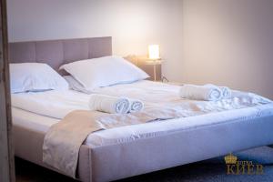 ein Bett mit weißer Bettwäsche und Handtüchern darauf in der Unterkunft Hotel Kiev in Weliko Tarnowo